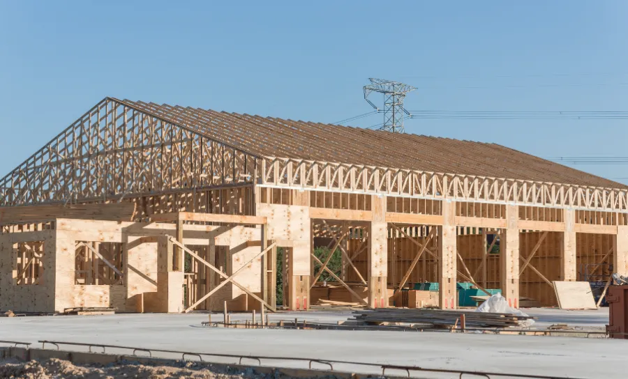 Large commercial building under construction showing structural wood framing and roof truss system